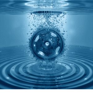 Metalni zupčanik uronjen u plavu vodu s mjehurićima koji simboliziraju ultrazvučno čišćenje složenih predmeta.